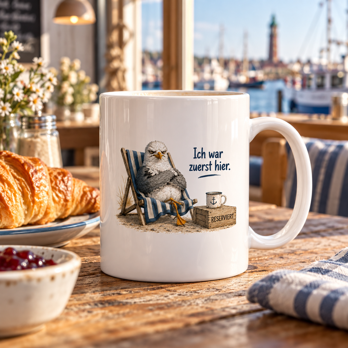 Weiße glänzende Keramiktasse mit Möwe im Strandstuhl und Spruch Ich war zuerst hier beim Frühstück im Hafencafé.