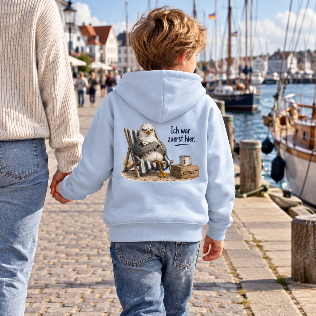 Kind von hinten im hellblauen Kinder-Hoodie mit Möwe Alpha als Backprint auf einer Hafenpromenade.