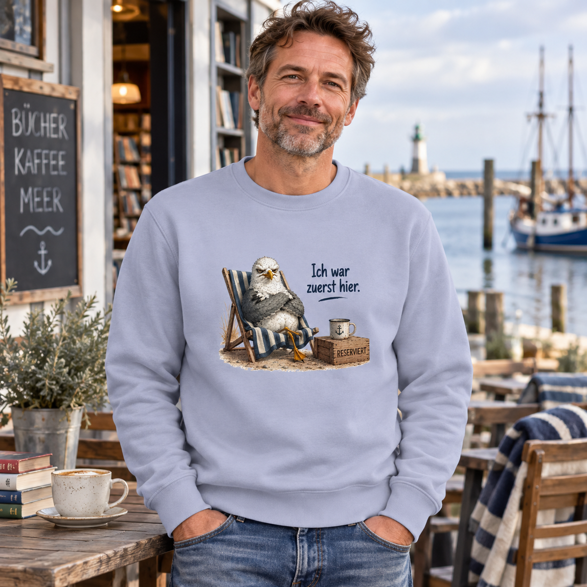 Mann im Serene-Blue-Unisex-Sweatshirt mit Möwe Alpha und Ich war zuerst hier als Frontprint am Hafencafé.