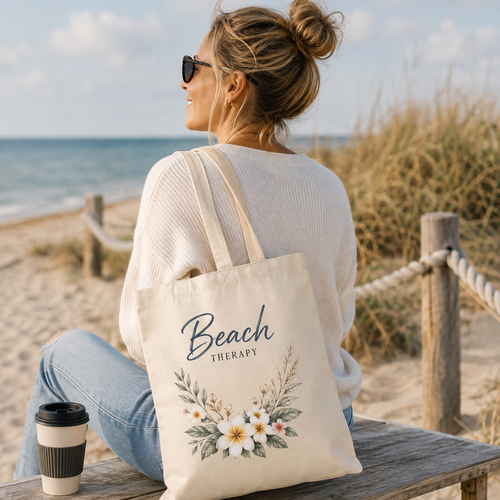 Frau am Strand mit naturfarbener Nomavé Stofftasche „Beach Therapy“ mit floralem Design