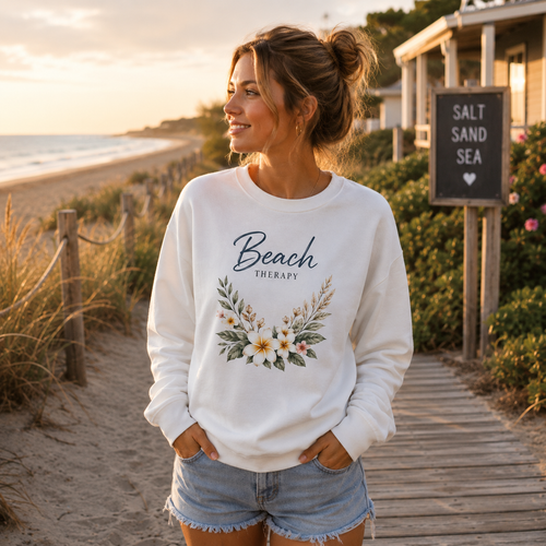 Frau im weißen Beach Therapy Sweatshirt mit floralem Strandmotiv am Meer