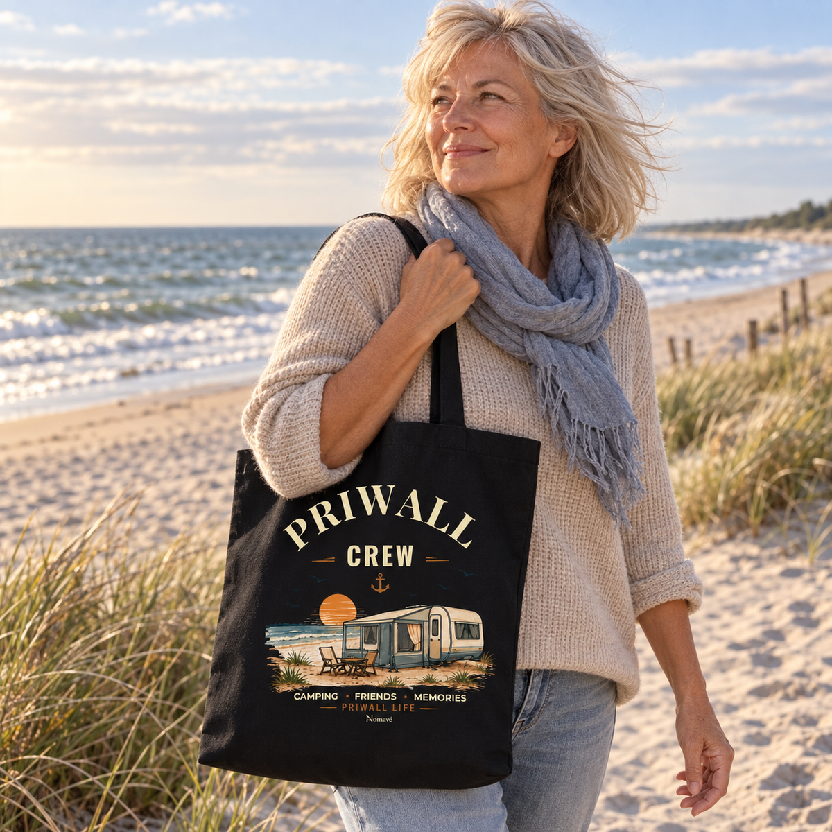 Schwarze Bio-Baumwolltasche mit Priwall-Crew-Motiv bei einem Strandspaziergang an der Ostsee