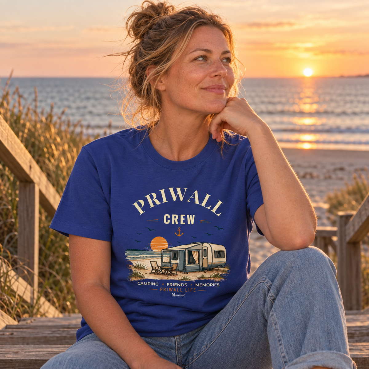 Frau im worker-blauen Bio-Heavy Shirt mit Priwall-Crew-Motiv auf einer Strandtreppe