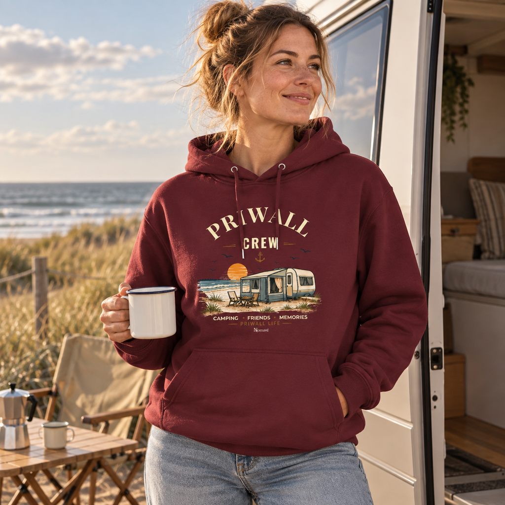 Frau im burgunderfarbenen Bio Hoodie mit Priwall-Crew-Motiv bei einer Roadtrip-Pause am Meer
