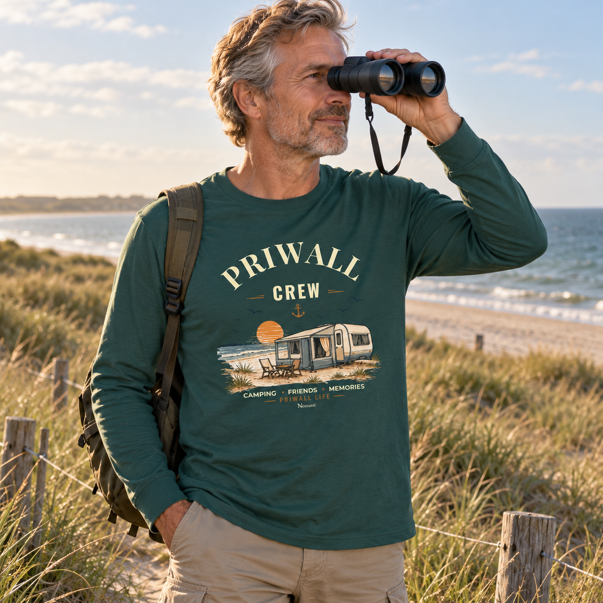 Mann im glazed-grünen Bio Longsleeve mit Priwall-Crew-Motiv auf einem Ostsee-Küstenweg