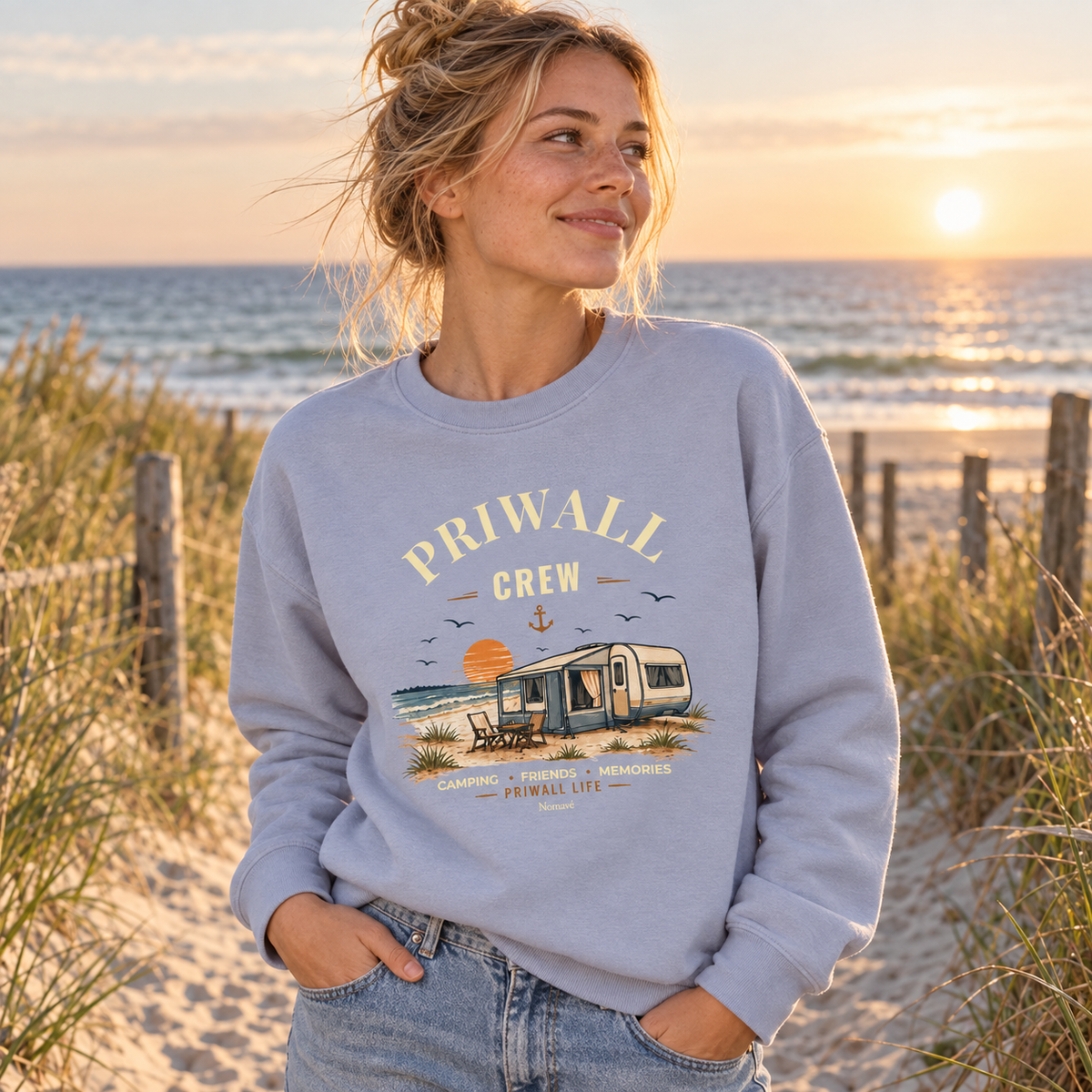 Frau im serene-blauen Bio Sweatshirt mit Priwall-Crew-Motiv am Strandzugang