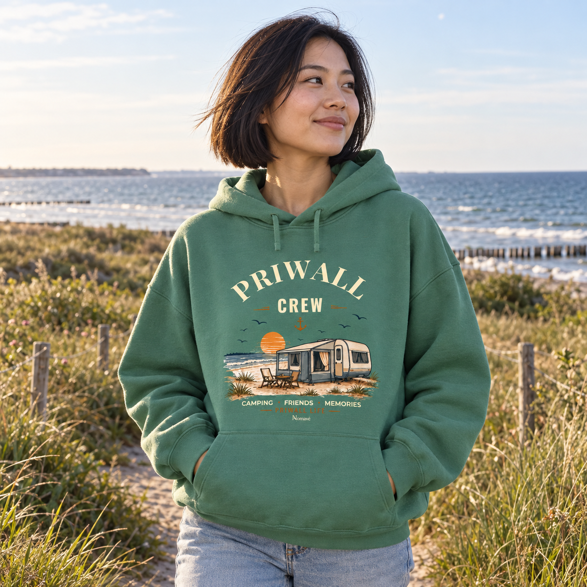 Frau im Green-Bay Damen Bio Boxcut Hoodie mit Priwall-Crew-Motiv auf einem Küstenweg