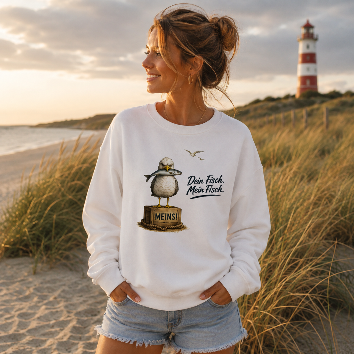 Frau trägt weißes Möwen Sweatshirt mit „Dein Fisch. Mein Fisch.“ Motiv am Strand – maritime Küstenmode von Nomavé
