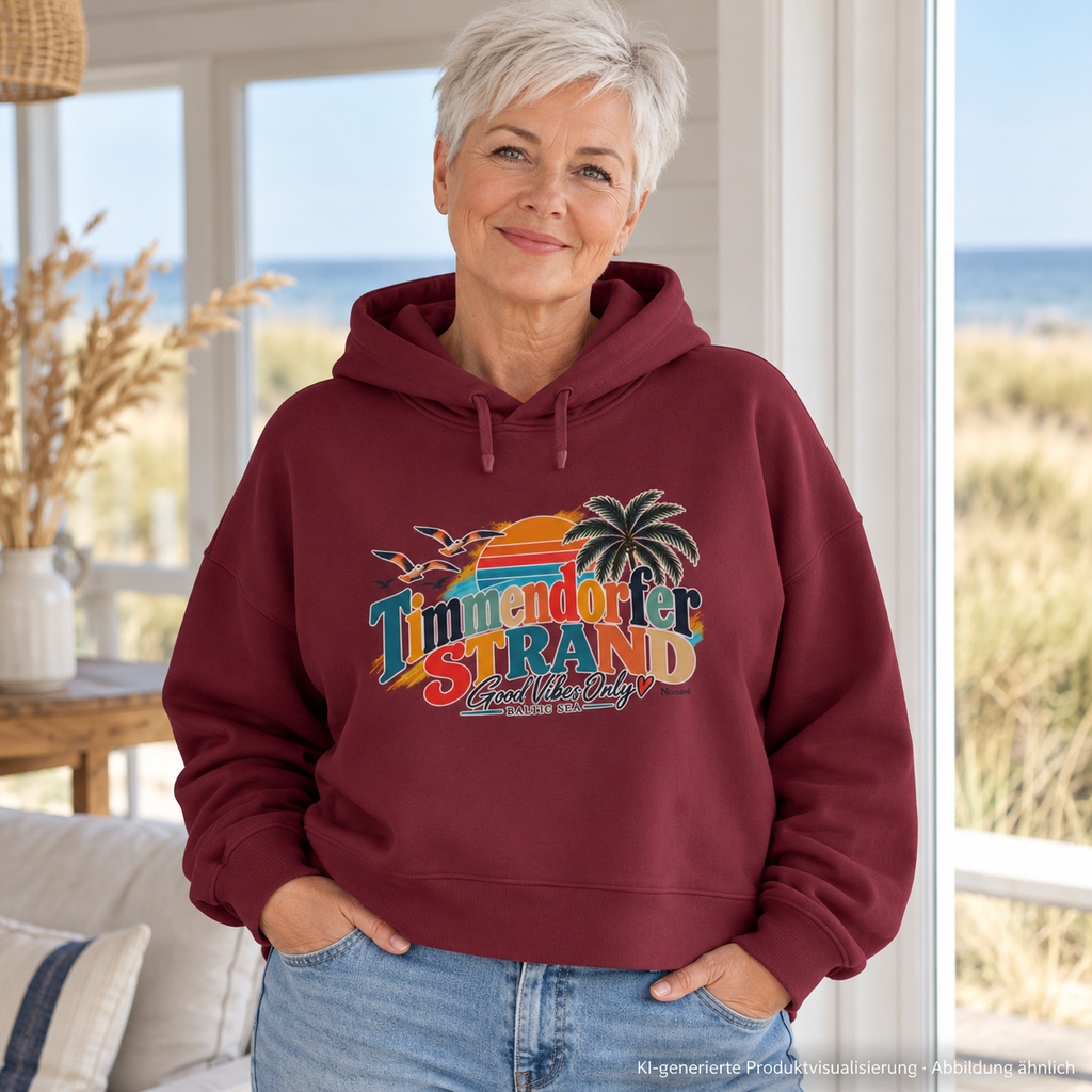 KI-generierte Produktvisualisierung: Frau im Burgundy Damen-Boxcut-Hoodie mit Good-Vibes-Only-Frontprint am Fenster eines Ferienhauses.