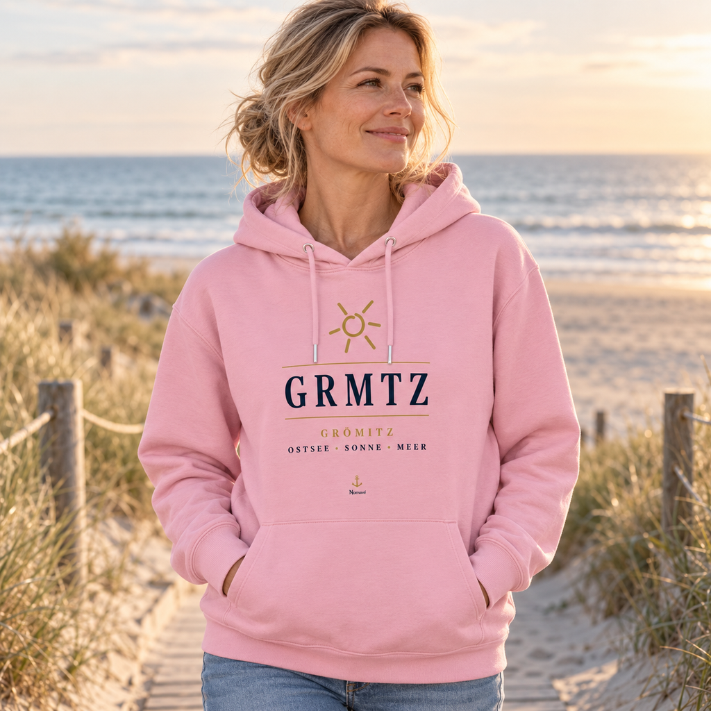 Frau trägt einen GRMTZ Grömitz Bio Hoodie in Cotton Pink am Ostseestrand