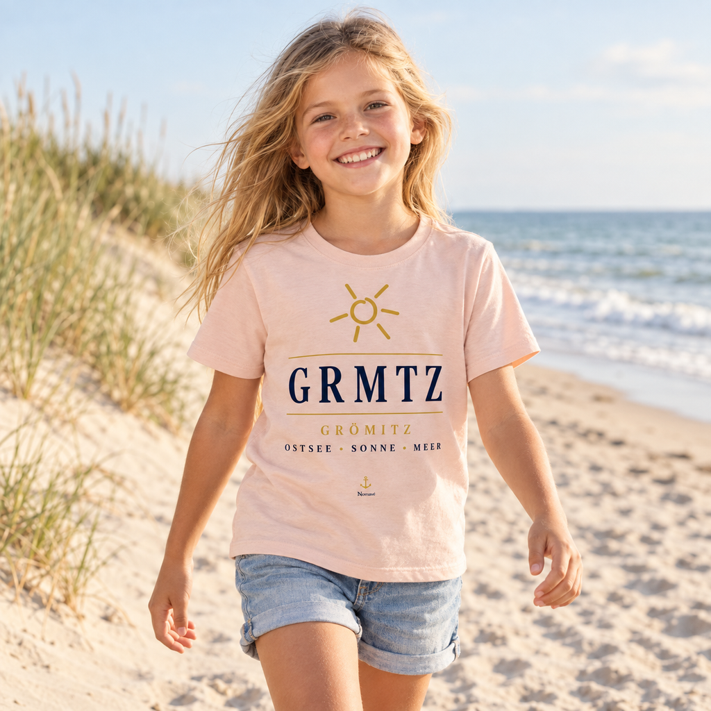 Mädchen trägt das GRMTZ Grömitz Kinder Bio-T-Shirt in Fraiche Peche am Ostseestrand