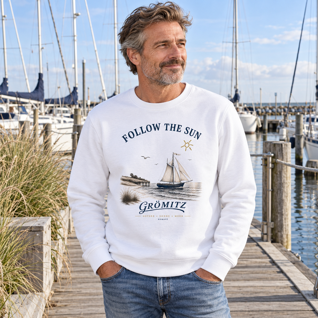 Mann trägt das weiße Grömitz Follow the Sun Bio-Unisex-Sweatshirt am Yachthafen
