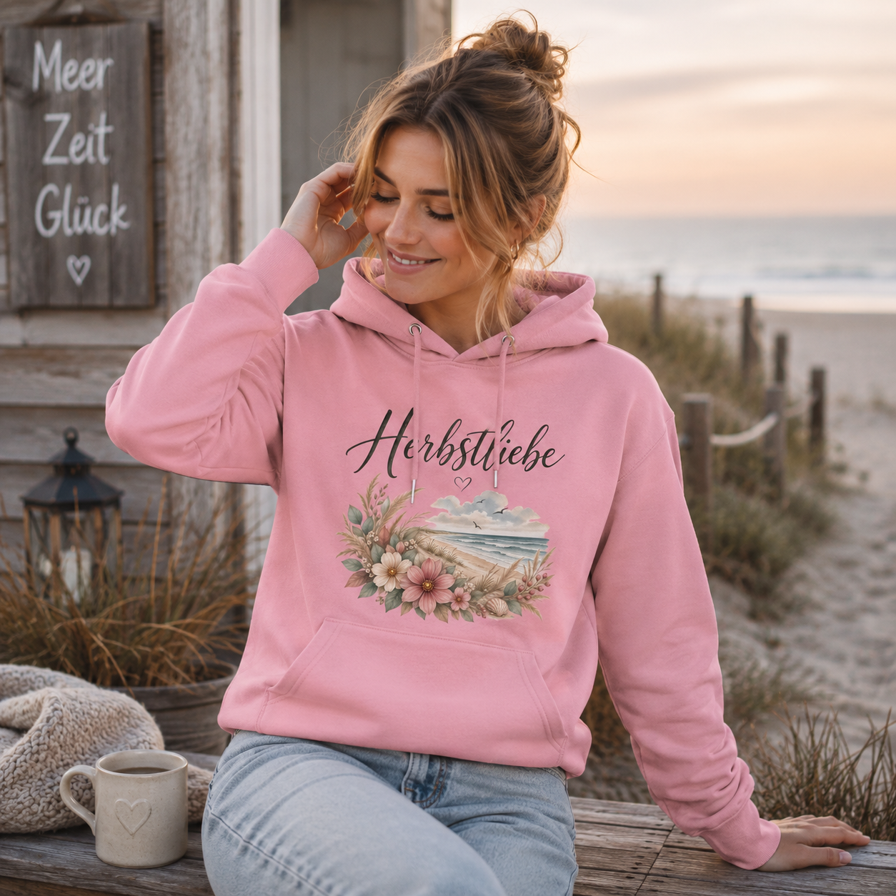 Junge Frau trägt rosa Herbstliebe am Meer Bio Hoodie in herbstlicher Küstenkulisse
