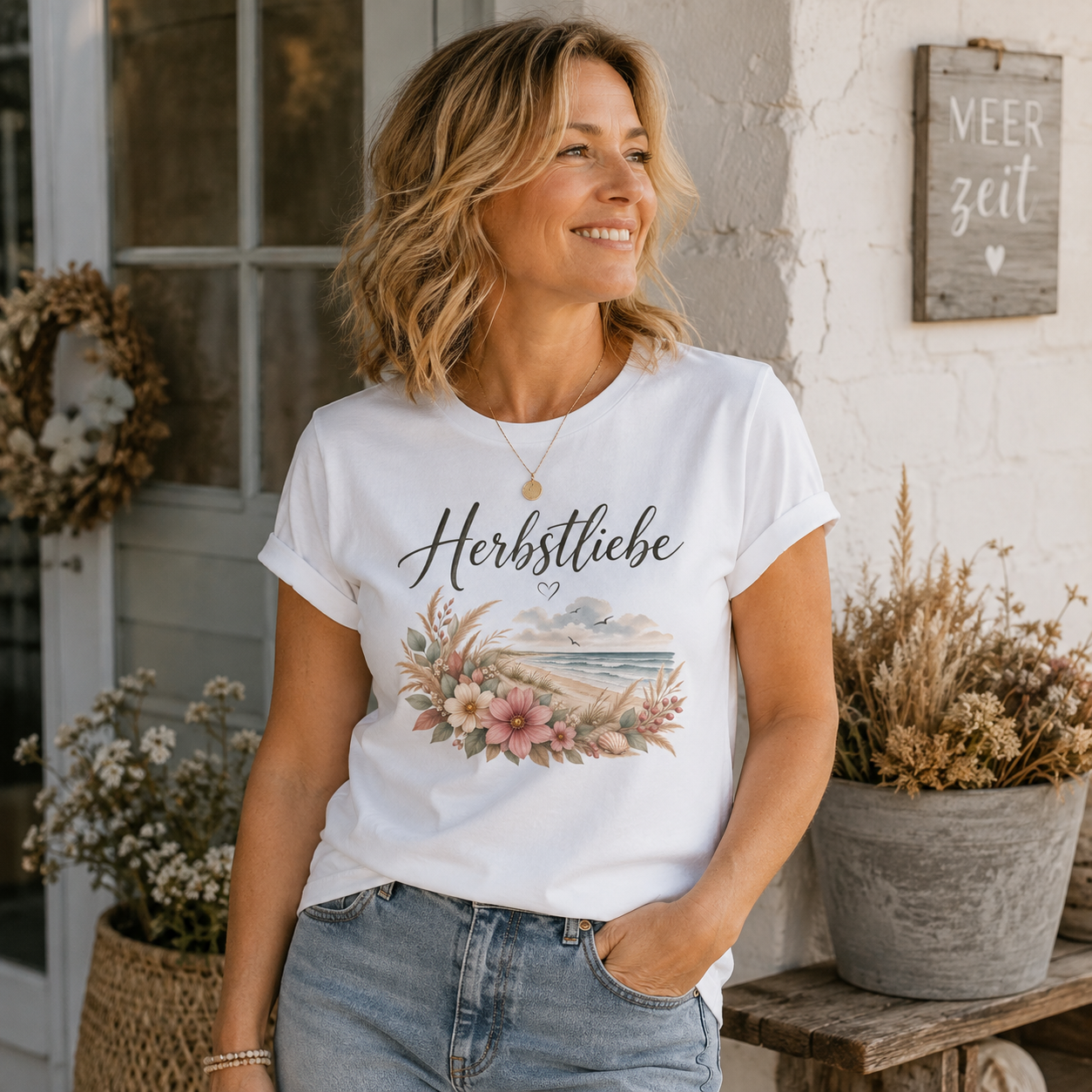 Frau mittleren Alters trägt weißes Ladies Bio T-Shirt Herbstliebe am Meer mit floralem Küstenmotiv