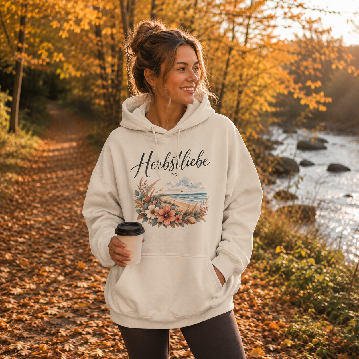 Frau trägt cremefarbenen Herbstliebe am Meer Oversized Hoodie von Nomavé in herbstlicher Natur