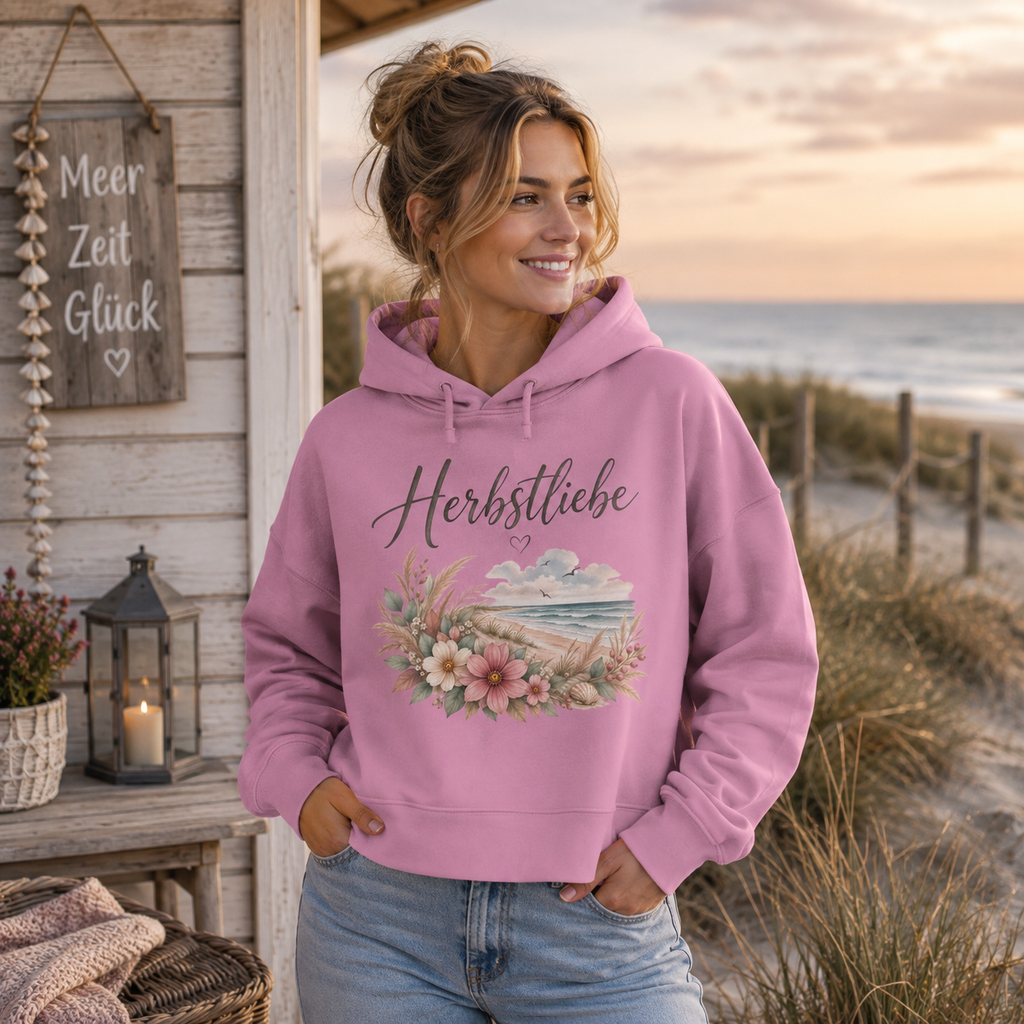 Junge Frau im pinken Herbstliebe Boxcut Hoodie am Meer – Autumn Coast Damen Hoodie mit floralem Küstenmotiv