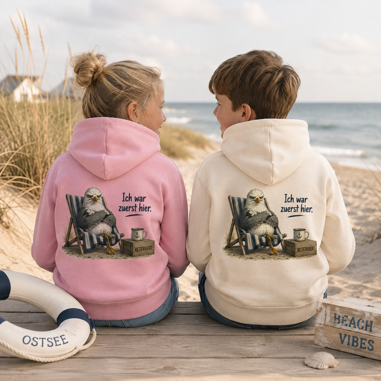 Zwei Kinder am Ostseestrand mit rosa und naturfarbenem Hoodie „Ich war zuerst hier“ und frechem Möwenmotiv von Nomavé