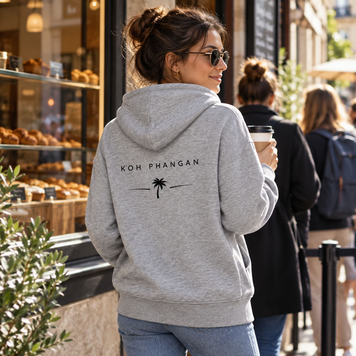 Heather Grey Bio Side Pocket Hoodie mit Koh-Phangan-Backprint vor einer Stadtbäckerei