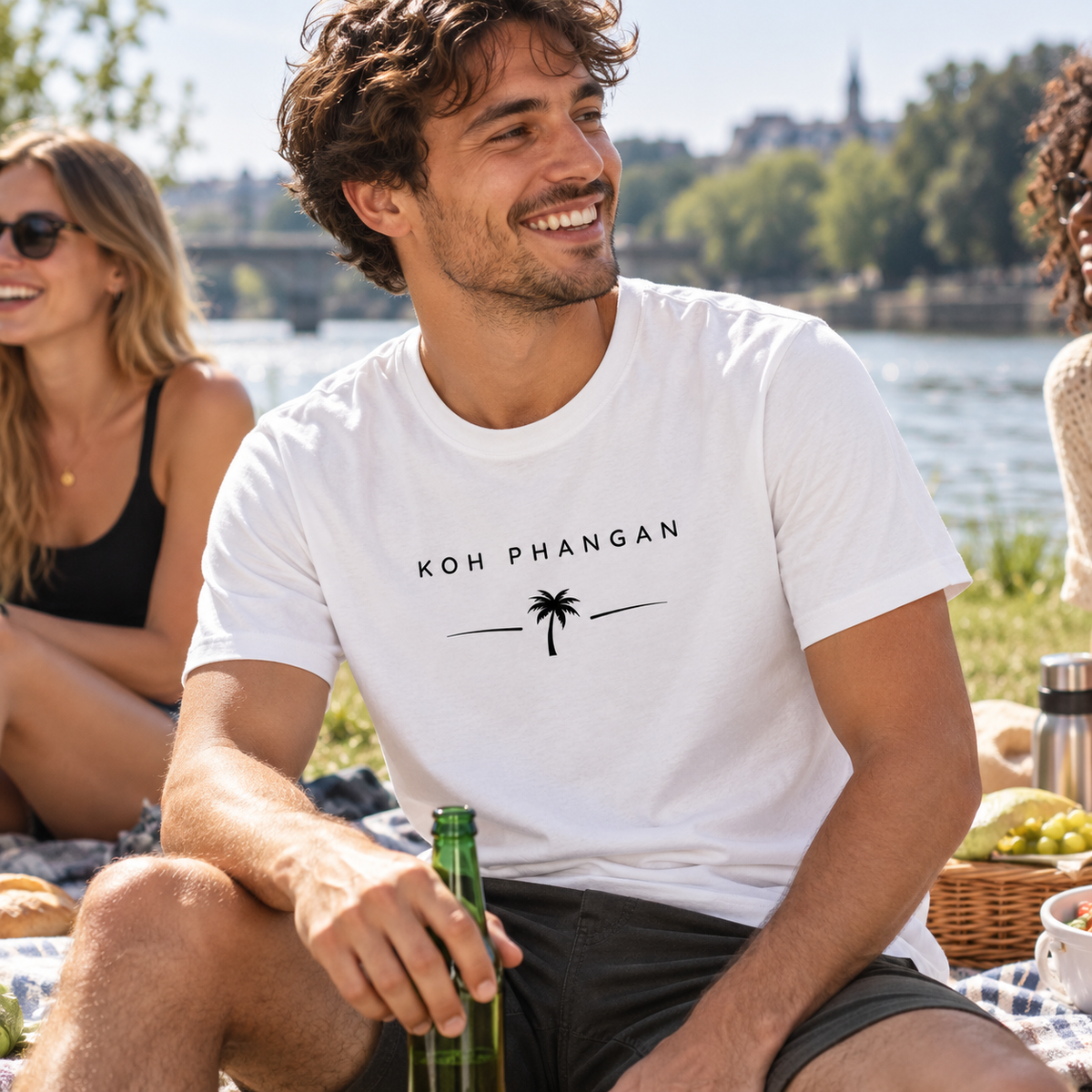 Mann im Bio T-Shirt mit Koh Phangan Minimal Palm Motiv bei einem Picknick am Fluss
