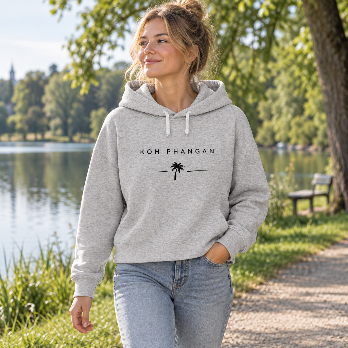 Frau im Bio Boxcut Hoodie mit Koh Phangan Minimal Palm Motiv bei einem Spaziergang am See