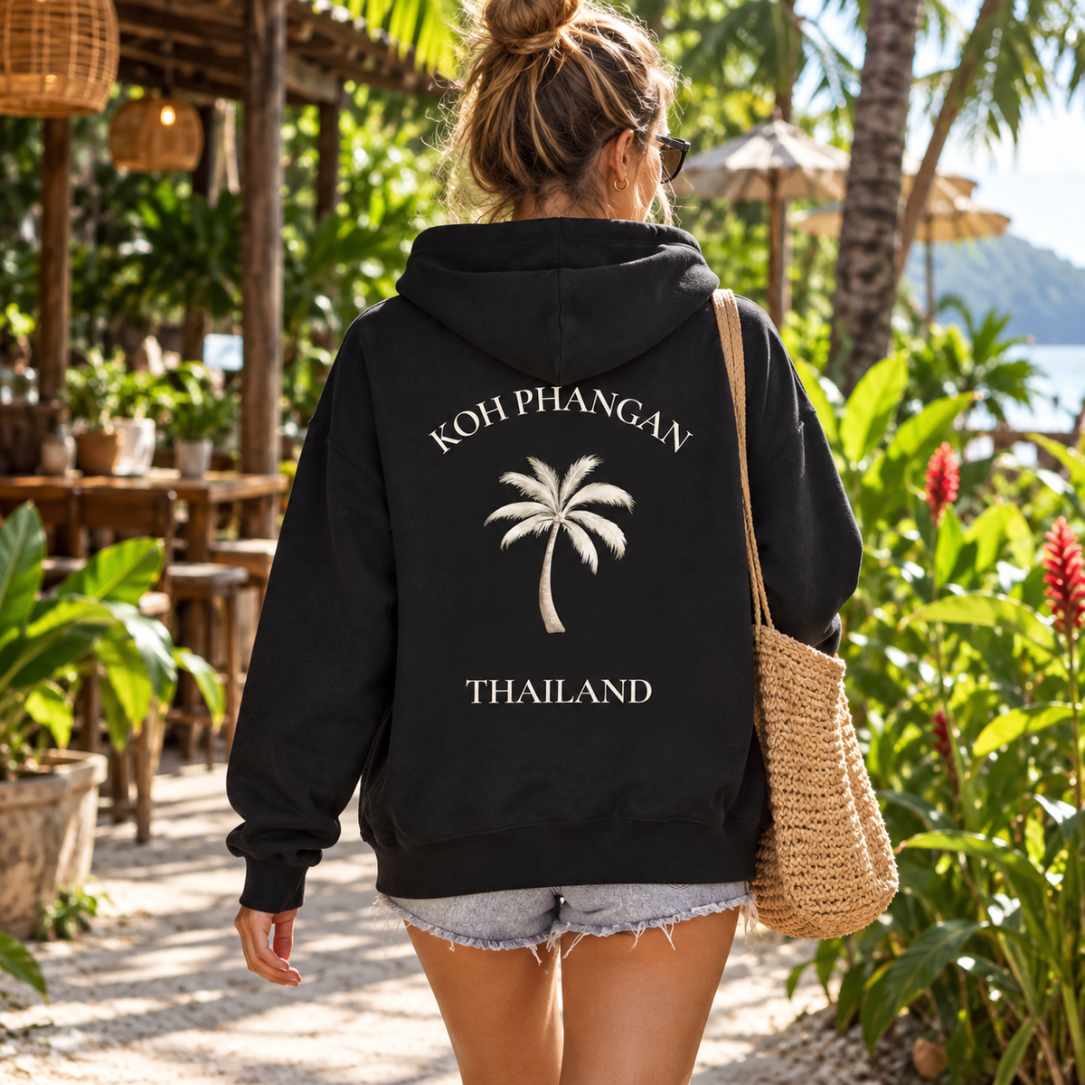 Frau mit schwarzer Bio Zipper Kapuzenjacke und Koh Phangan Mini Palm Backprint in einem thailändischen Garten