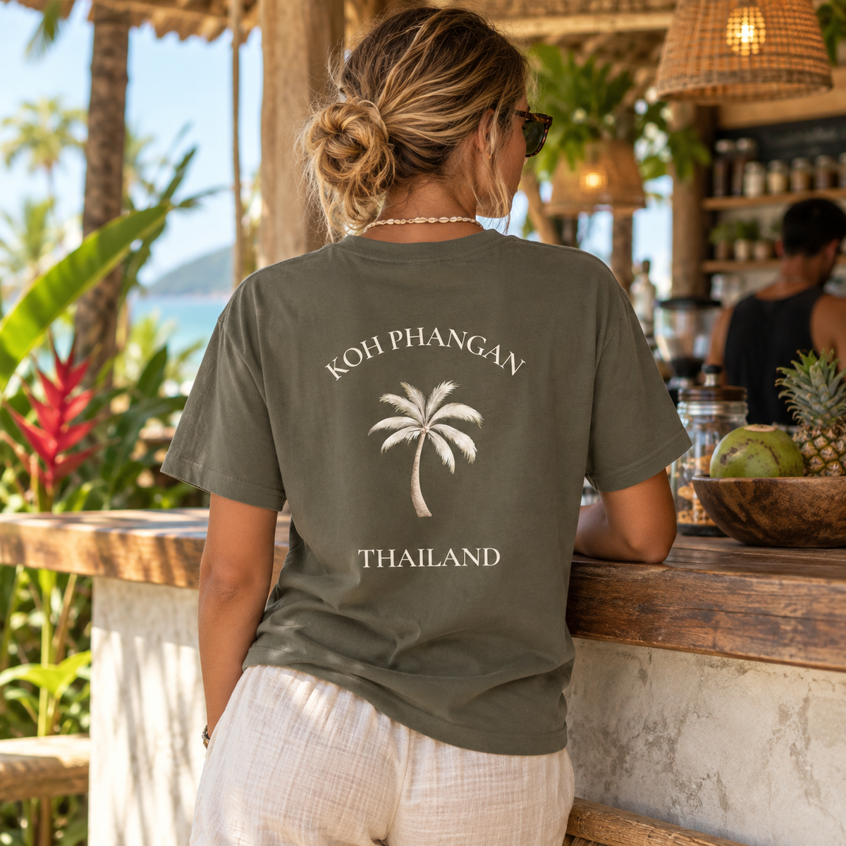 Bio T-Shirt in Khaki mit Koh Phangan Mini Palm Backprint in einem tropischen Café