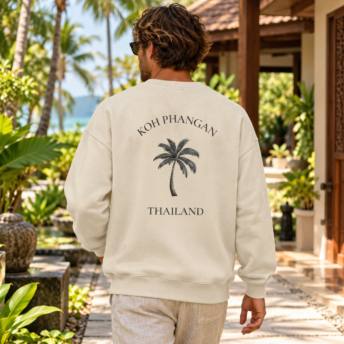 Bio Oversize Sweatshirt in Natural Raw mit Koh Phangan Mini Palm Rückenmotiv in einem tropischen Hotelgarten