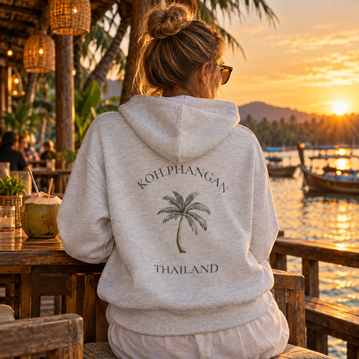 Bio Side Pocket Hoodie in Weiß mit Koh Phangan Mini Palm Rückenmotiv in einem Restaurant am Wasser