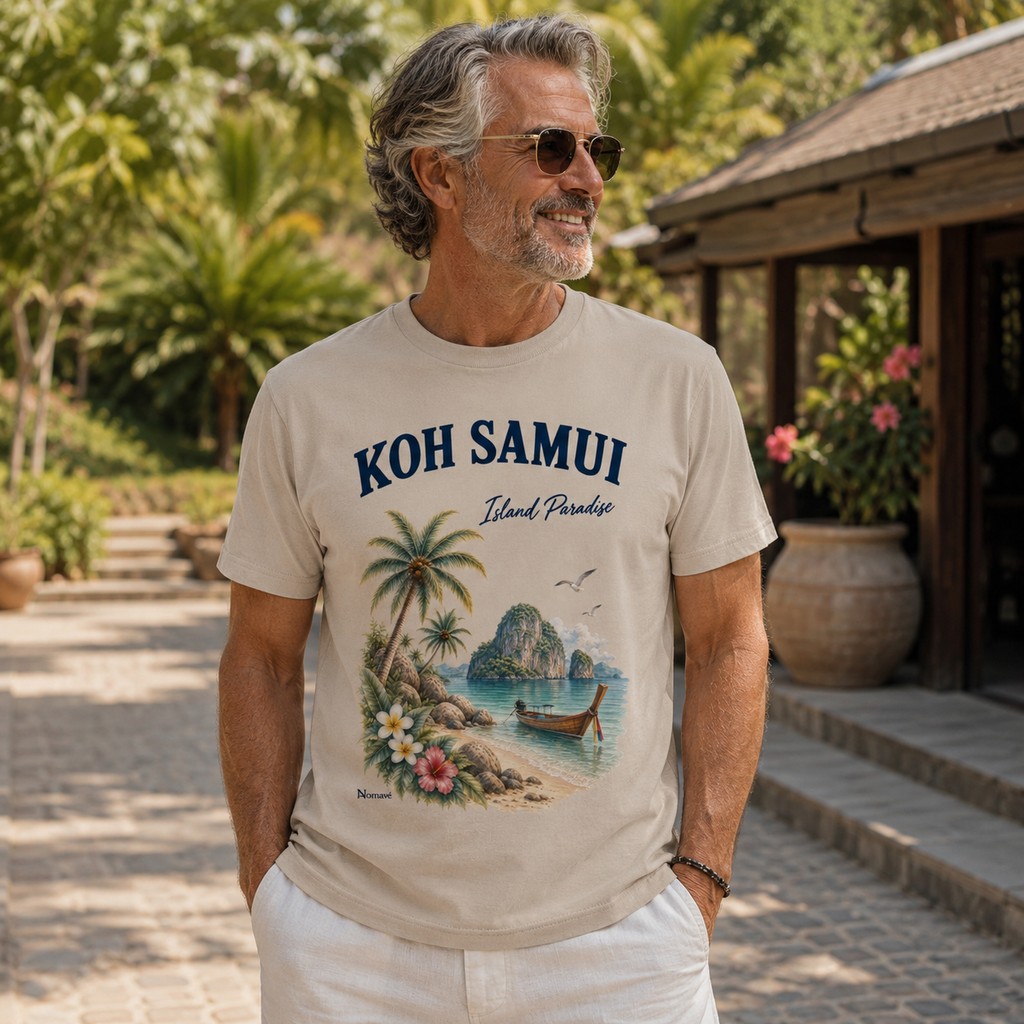 Mann trägt das Nomavé Koh Samui Island Paradise T-Shirt mit tropischem Thailand-Motiv aus Palmen, Longtailboot und Meer am Strand.