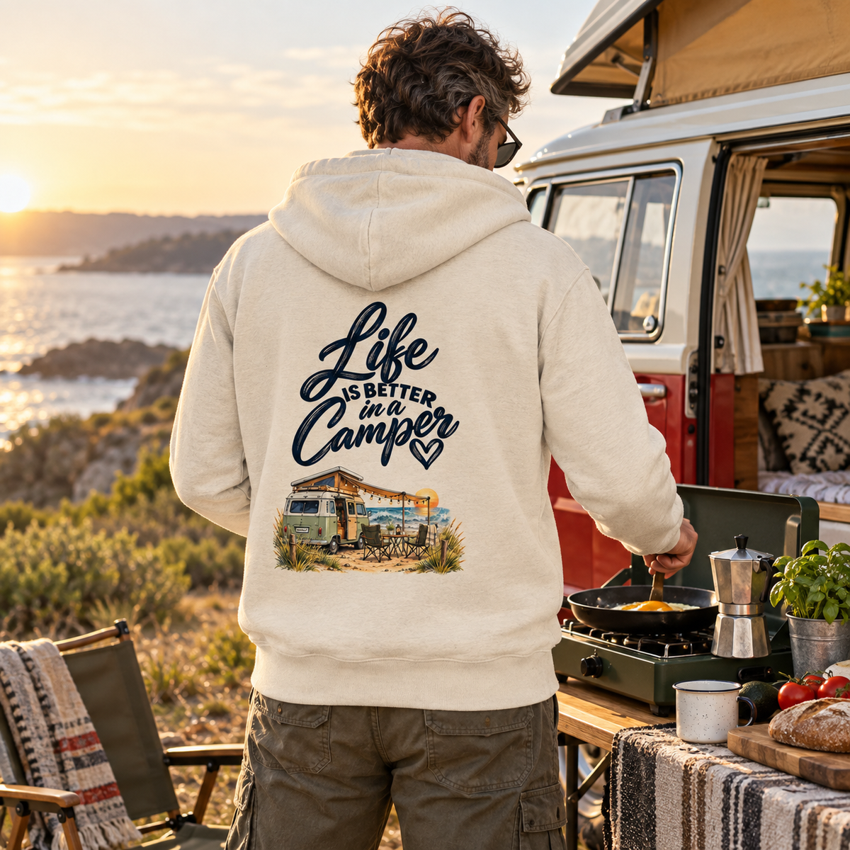 Mann mit Bio-Zipper und Life-is-better-in-a-Camper-Rückendruck beim Campingfrühstück vor Vintage-Camper
