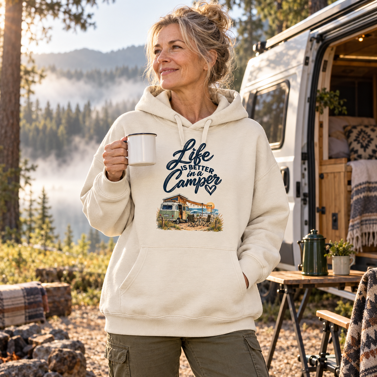 Frau im Bio-Oversize-Hoodie mit Camper-Motiv beim Morgenkaffee im Wald