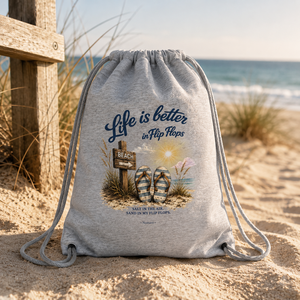 Grauer Nomavé Turnbeutel „Life is Better in Flip Flops“ am Sandstrand der Ostseeküste zwischen Dünen im warmen Morgenlicht – maritimer Lifestyle.