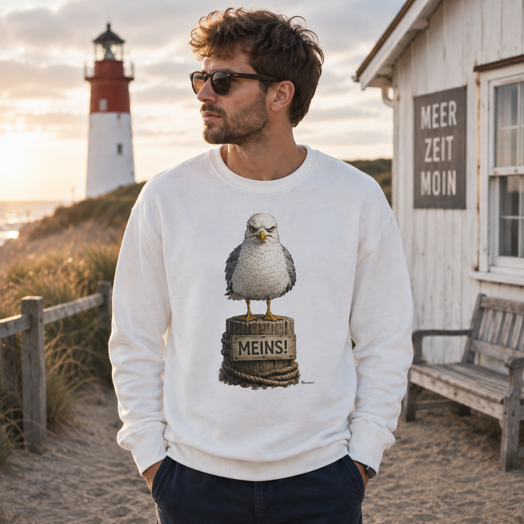 Mann trägt weißes Nomavé Möwen Sweatshirt mit MEINS Motiv an der Küste – maritimer Küstenhumor für Ostsee- und Nordseefans
