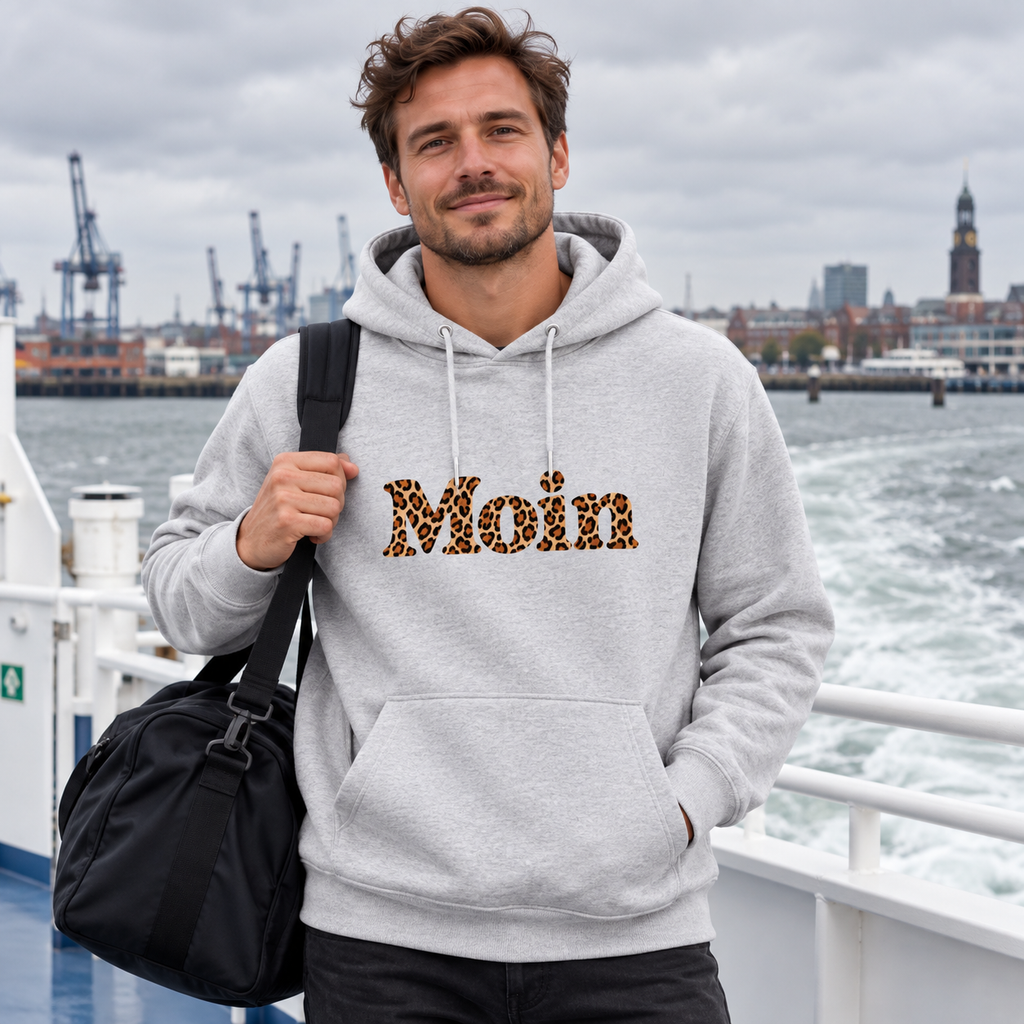 Mann im grauen Bio Hoodie mit Moin-Leoprint an Bord einer Küstenfähre