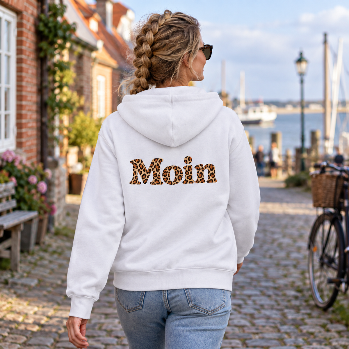 Weiße Bio Zipperjacke von hinten mit lesbarem Moin-Leoprint in einer Küstenstraße