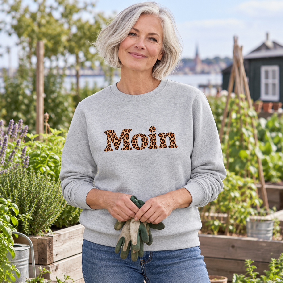 Frau im Bio Unisex Sweatshirt in Heather Grey mit Moin-Karamell-Leoprint als Frontprint im Kräutergarten