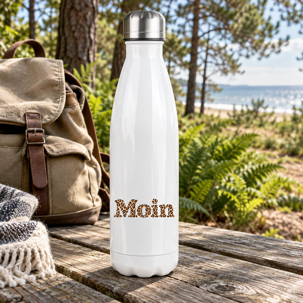 Weiße Edelstahl-Thermoflasche mit Silberdeckel und Moin-Karamell-Leoprint auf einem Picknicktisch am Küstenwald