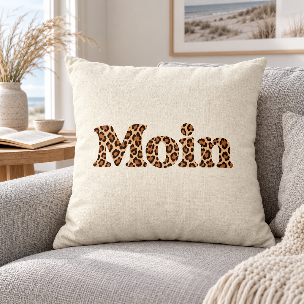 Naturfarbenes Kissen 40 × 40 cm mit Moin-Karamell-Leoprint auf einem hellgrauen Sofa