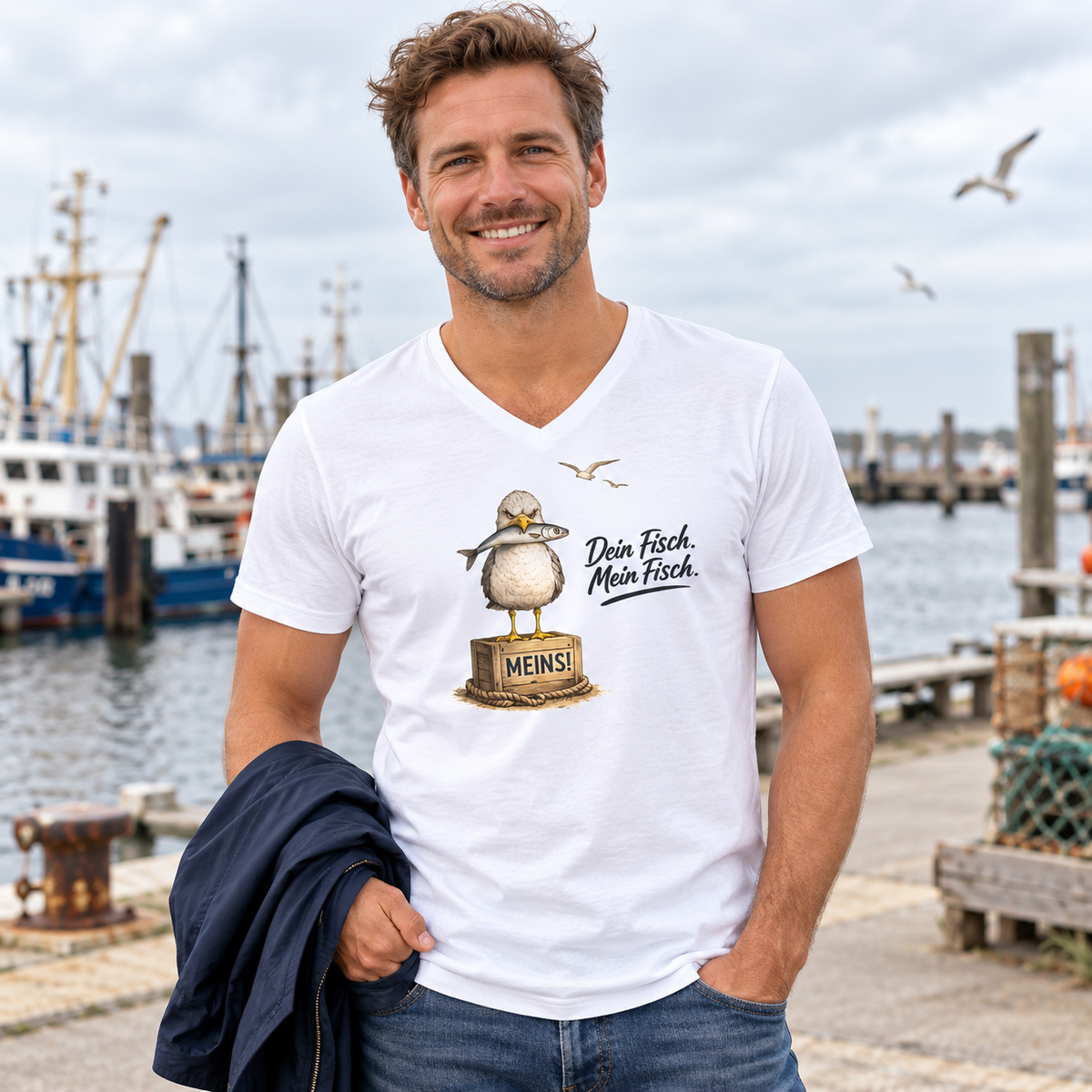 Mann im weißen Bio V-Neck T-Shirt mit Alpha-Möwe und Fisch als Frontprint am Fischereihafen