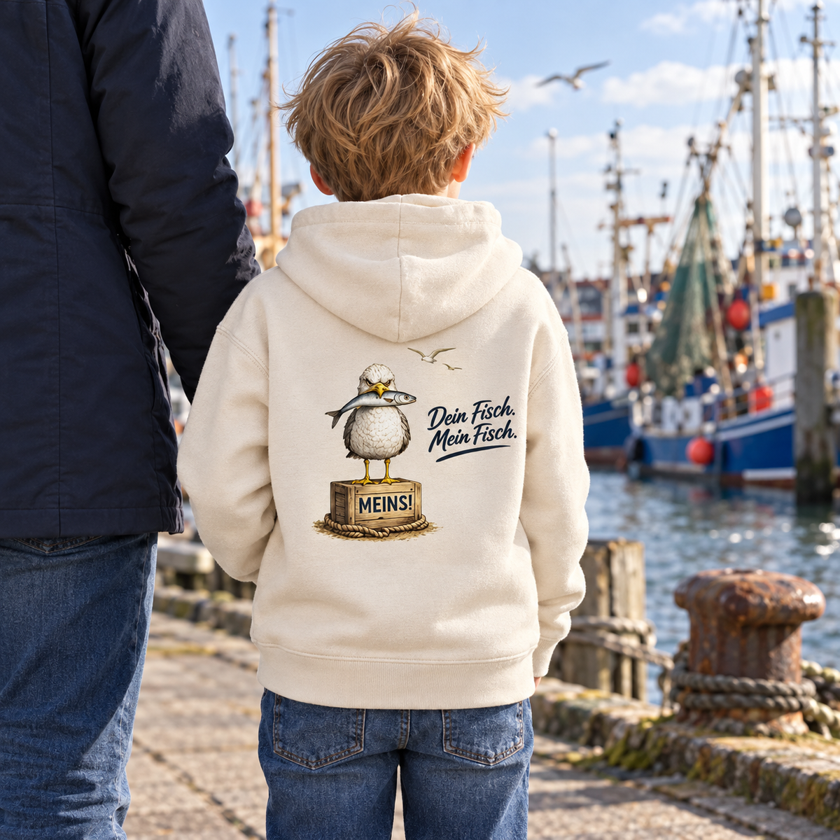 Kind im Kinder Bio Hoodie Natural Raw mit Möwe, Fisch und „Dein Fisch. Mein Fisch.“ als Backprint am Fischereihafen