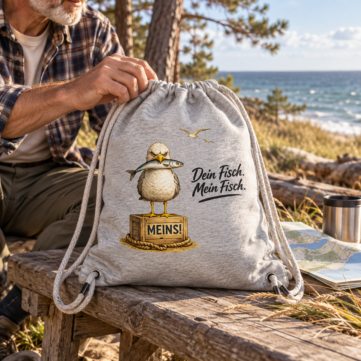 Heather-Grey Gym-Bag mit Fisch-Möwe und „MEINS!“-Kiste bei einem Küstenausflug