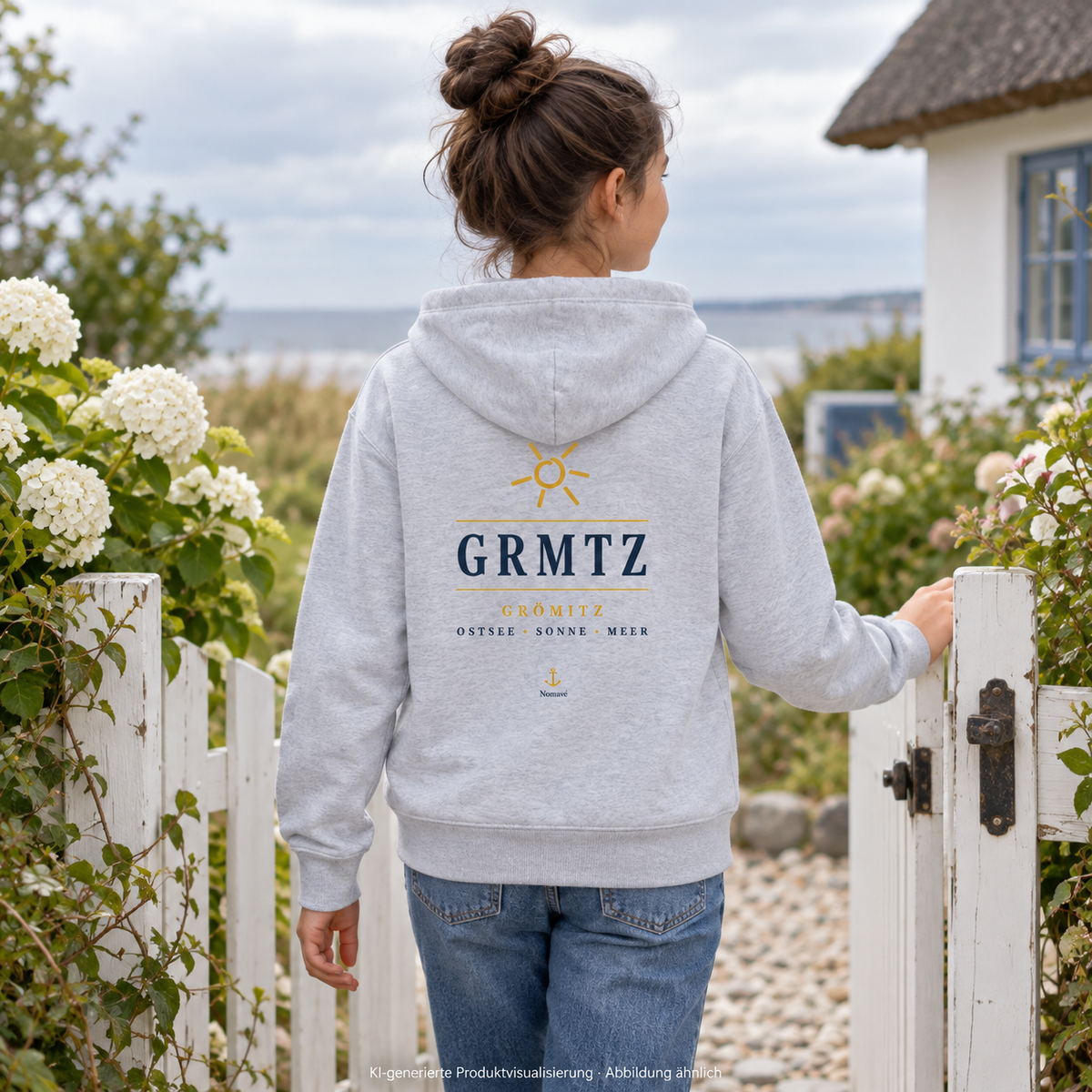 Mädchen im GRMTZ Grömitz Kinder-Bio-Hoodie in Heather Grey am Gartentor – Rückendruck mit Sonne; KI-Visualisierung.