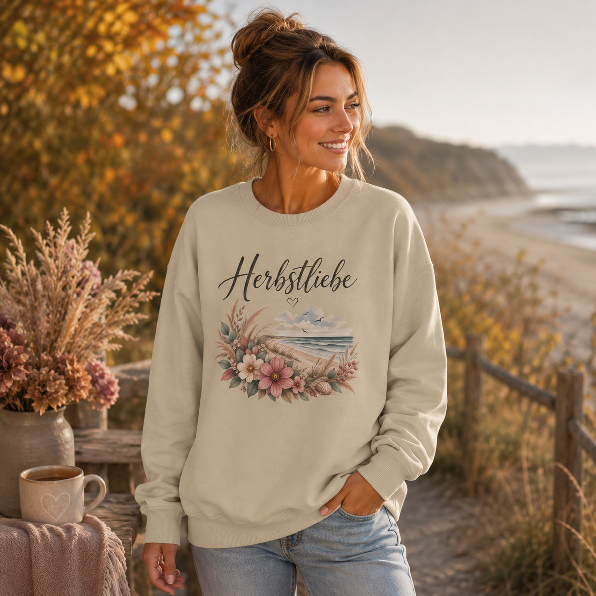 Frau trägt Nomavé Herbstliebe Oversize Sweatshirt mit floralem Küstenmotiv in herbstlicher Landschaft am Meer