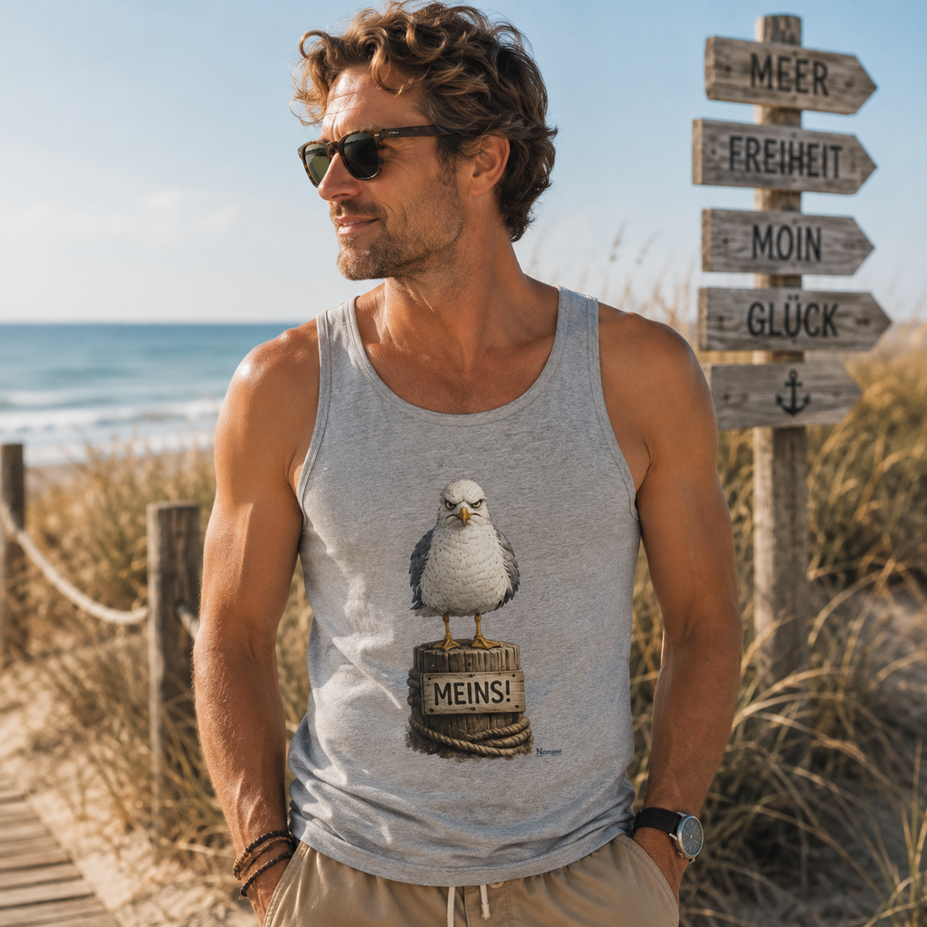 Mann trägt das graue Bio Tanktop „MEINS!“ aus der Nomavé Küstenhumor-Kollektion am Ostseestrand. Sommerliches Lifestyle-Bild mit Dünen, Meer und maritimer Wegweiser-Kulisse.
