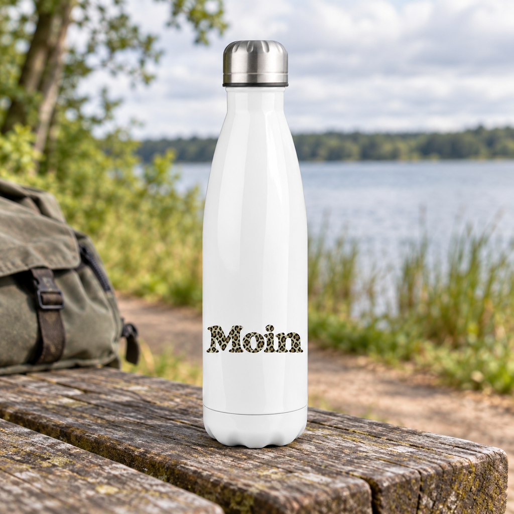Weiße Edelstahl-Thermoflasche mit silbernem Deckel und Moin-Leoprint in Sage Green im unteren Bereich auf einer Bank am See.
