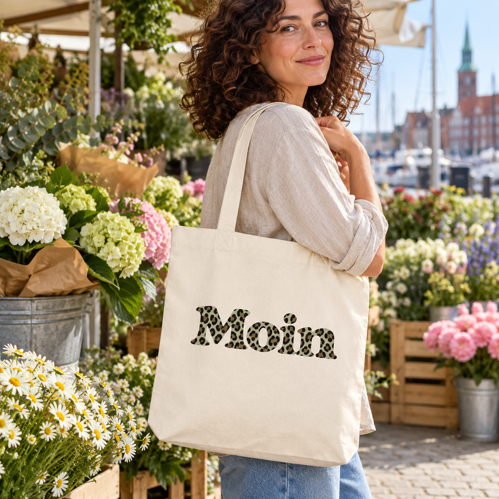 Frau mit naturfarbenem Moin-Leo-Sage-Green-Shopper auf einem Blumenmarkt.