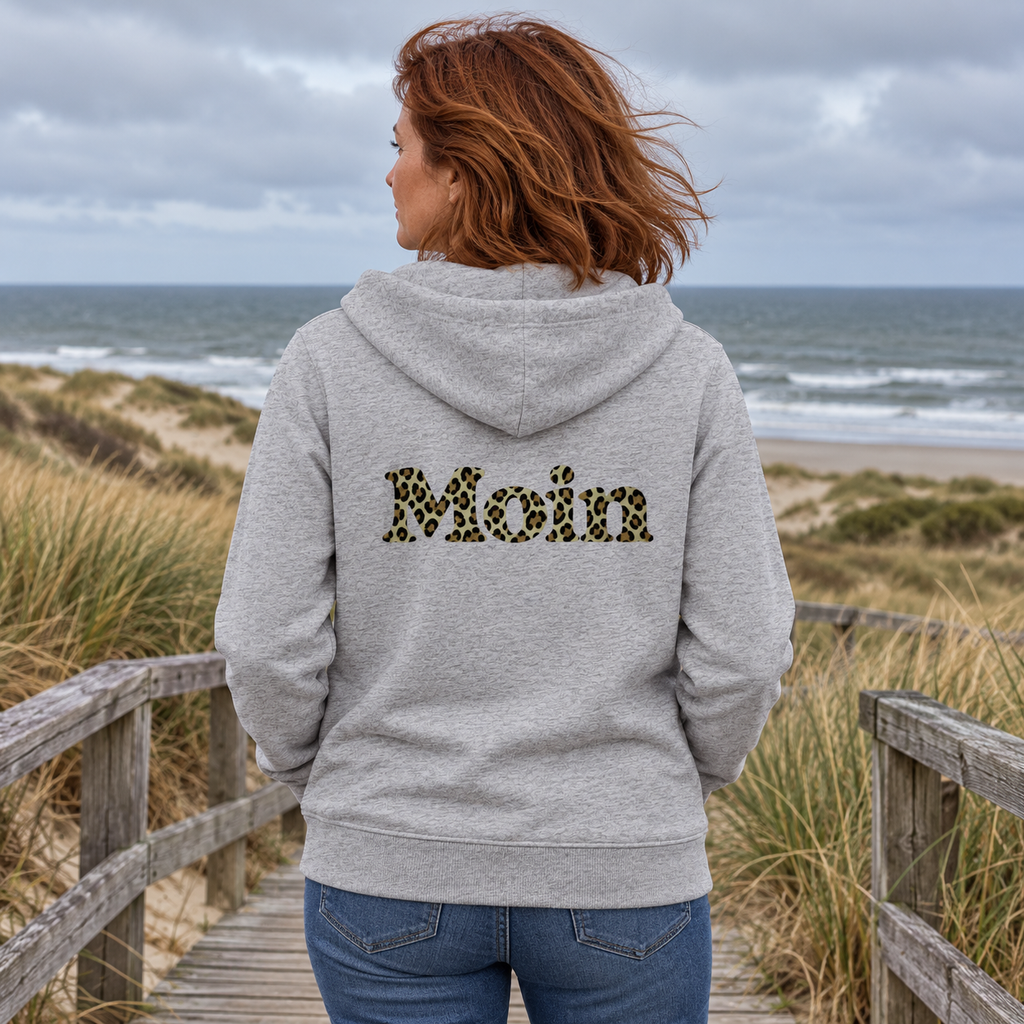 Frau auf einem Dünensteg mit graumelierter Zipper-Kapuzenjacke und Moin-Leo-Sage-Green-Backprint.