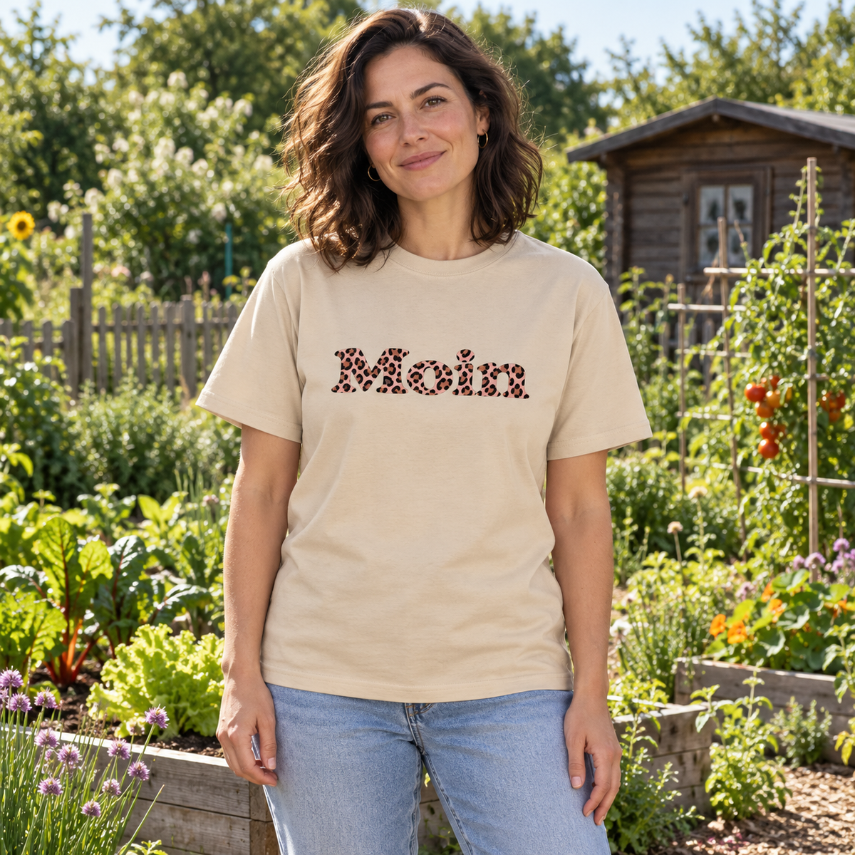 Frau im Garten mit naturfarbenem Heavy-Cotton-T-Shirt und Moin-Leo-Blush-Pink-Frontprint.
