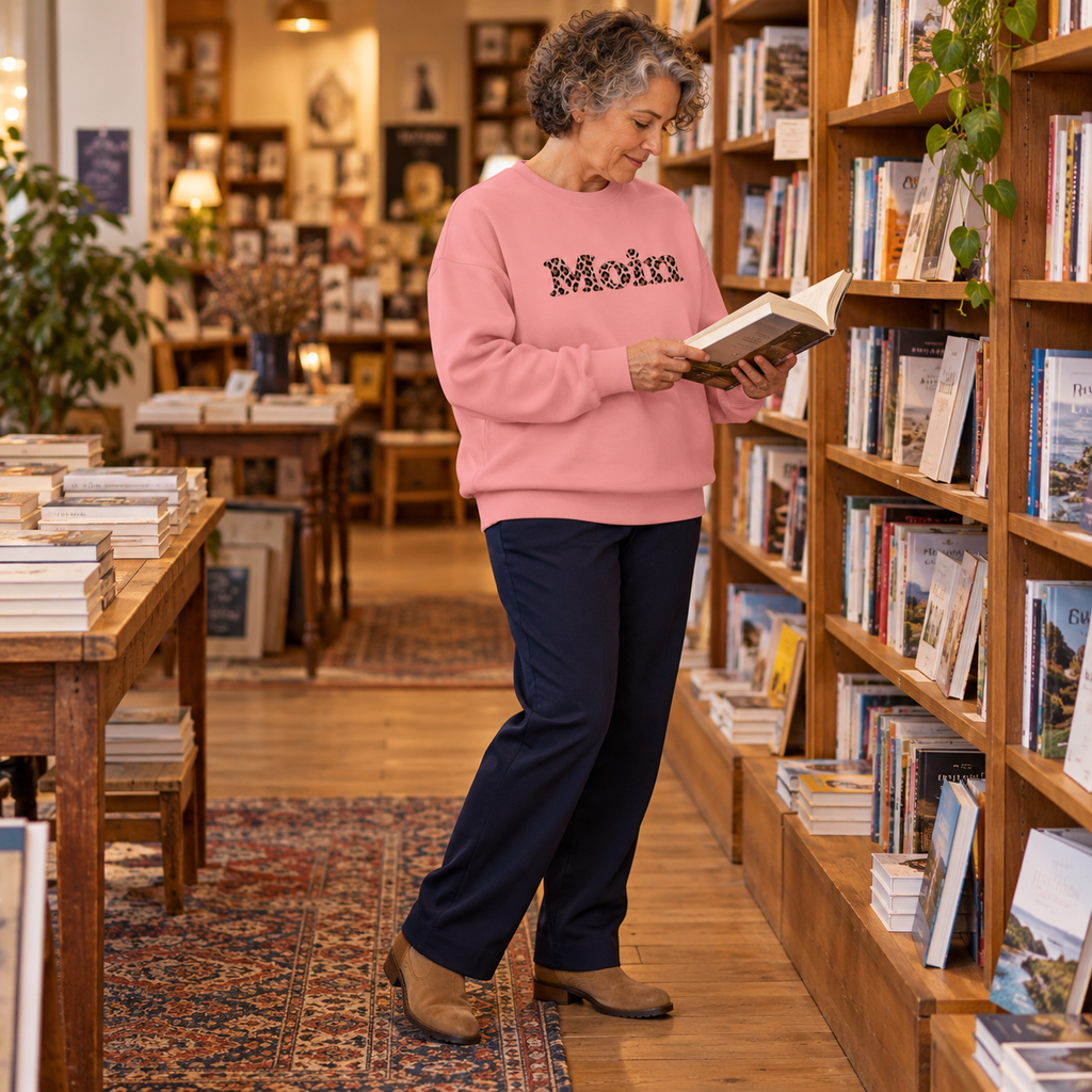 Frau blättert in einer Buchhandlung im Bio-Oversize-Sweatshirt Pink Joy mit Moin-Leo-Frontprint.