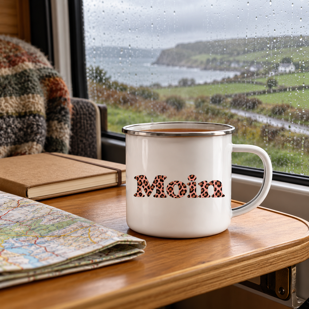 Emaille-Tasse mit Silberrand und Moin-Leo-Blush-Pink-Motiv auf einem Campertisch neben Karte und Notizbuch.